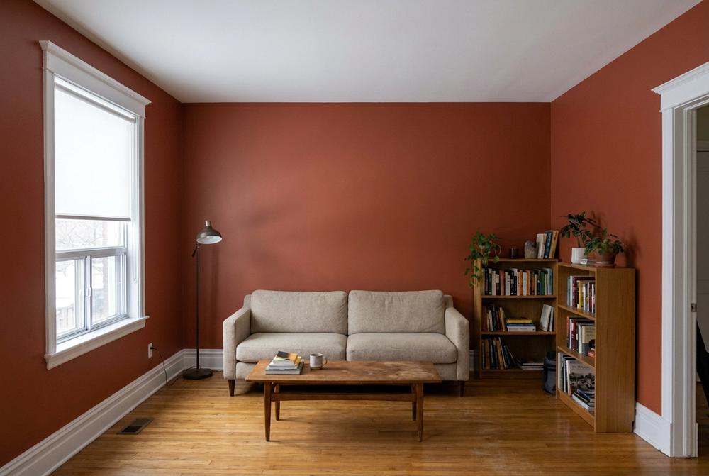 Salon peint en rouge brique, plancher de chêne, canapé en laine